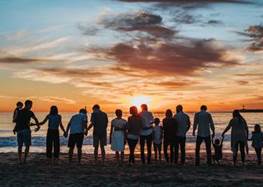Barn och vuxna på en strand vid solnedgång