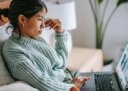 Kvinna i soffa som kollar på datorn