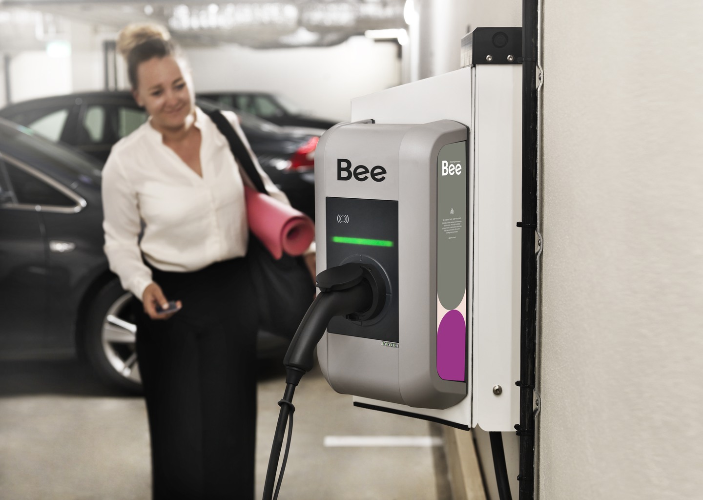 Kvinna står vid laddbox för elbil