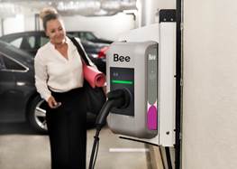 Kvinna står vid laddbox för elbil