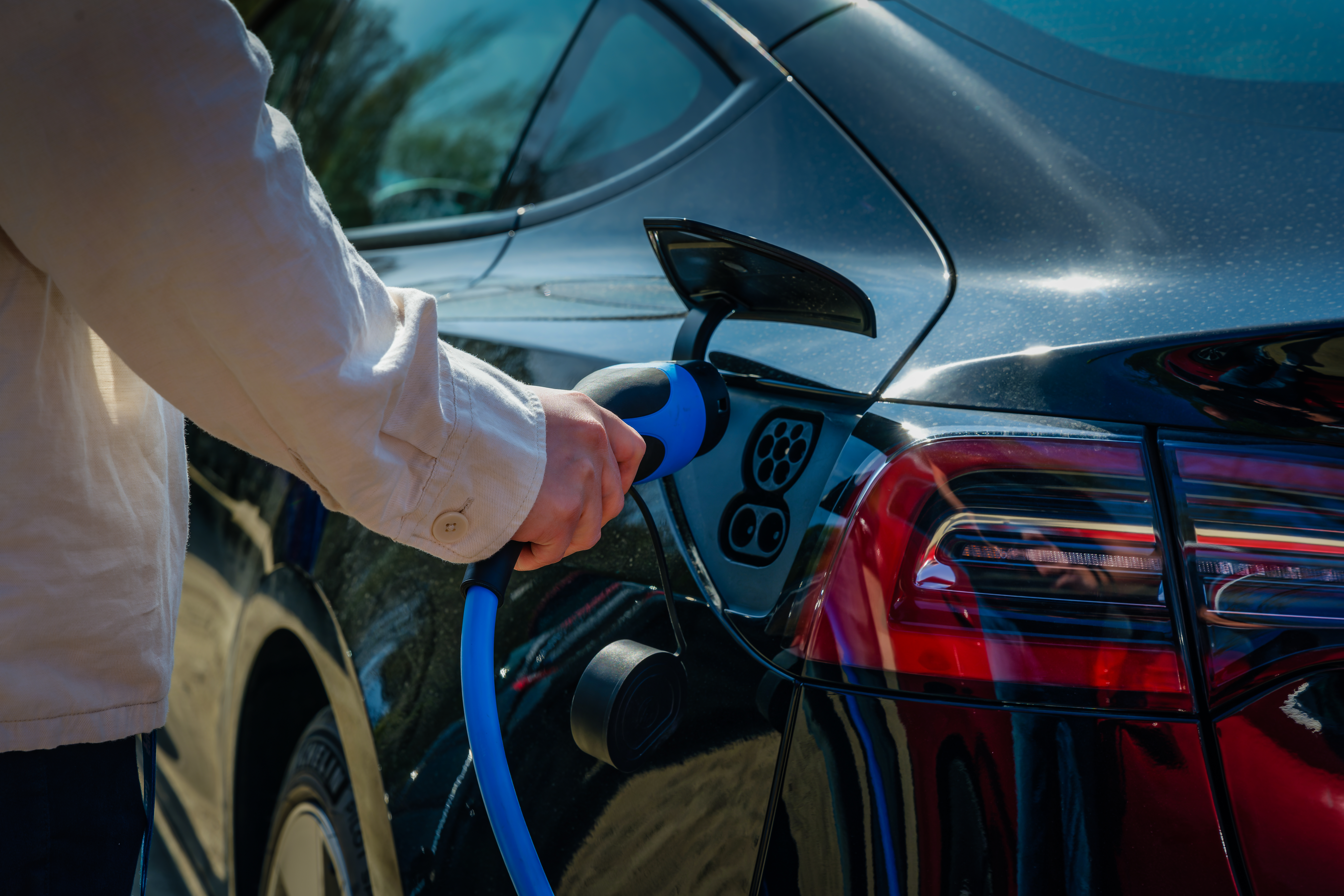 Person kopplar in laddare i elbil